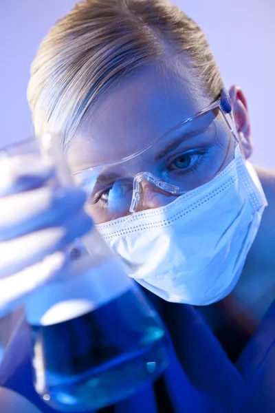 Médica cientista com frasco de líquido azul em laboratório — Fotografia de Stock
