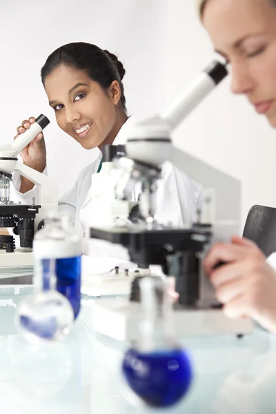Kadın bilimsel araştırma ekibi bir laborator mikroskoplar kullanılarak — Stok fotoğraf