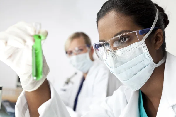 Equipo de investigación científica femenina con solución verde en laboratorio —  Fotos de Stock