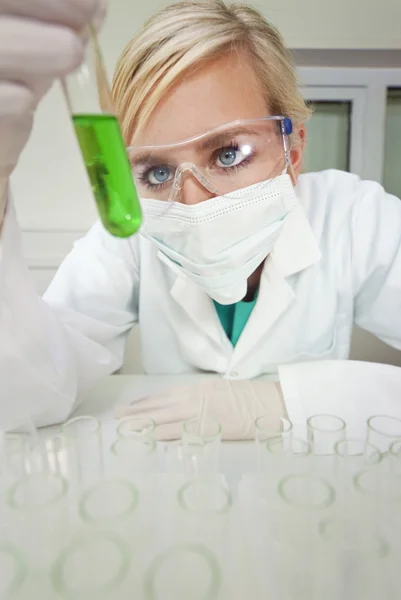 Vrouwelijke wetenschapper met reageerbuis van groene vloeistof in laboratorium — Stockfoto