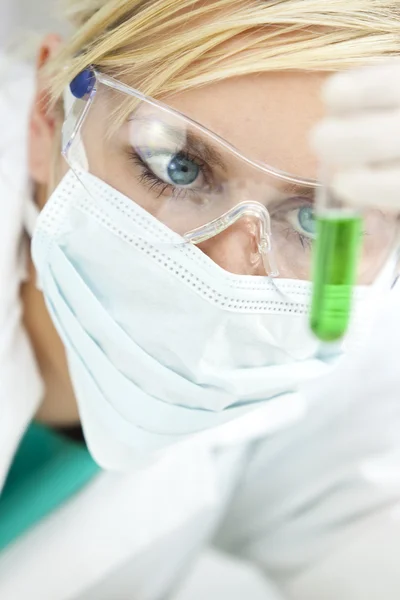 Vrouwelijke wetenschappelijk onderzoeker met groene oplossing in laboratorium — Stockfoto