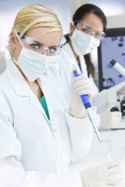 Cientista de pesquisa feminina com pipeta e frasco em laboratório — Fotografia de Stock