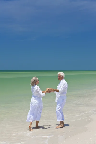 Feliz pareja mayor bailando sosteniendo las manos en una playa tropical —  Fotos de Stock