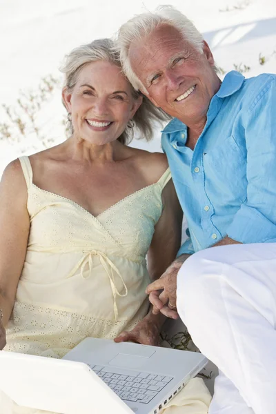 Glückliches Seniorenpaar mit Laptop am Strand — Stockfoto