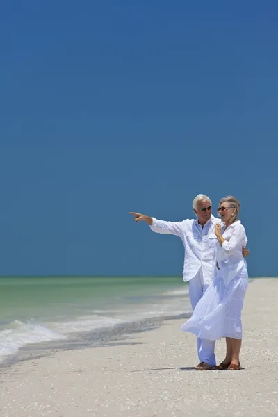 Szczęśliwa para starszy, wskazując na morze na tropikalnej plaży — Zdjęcie stockowe
