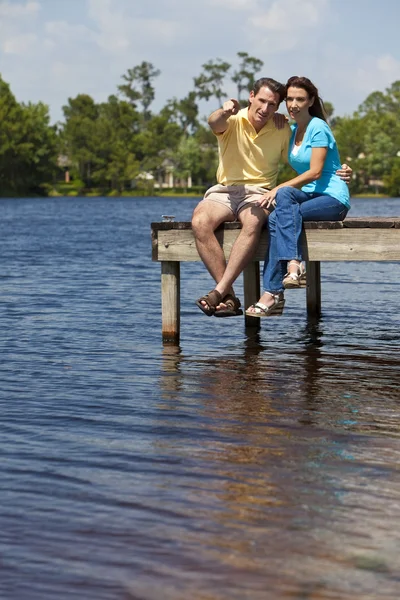 Homem e mulher felizes casal sentado em um cais perto do lago — Fotografia de Stock