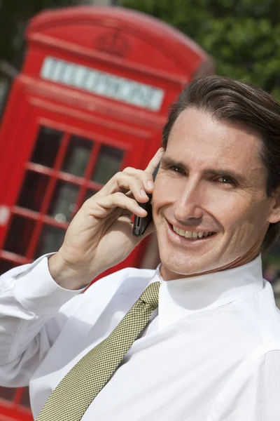 Uomo d'affari sul cellulare a Londra con scatola telefonica rossa — Foto Stock