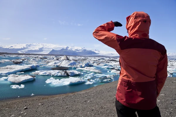 Caminhante feminina olhando para a lagoa cheia de Iceberg, Jokulsarlon, Icel — Fotografia de Stock