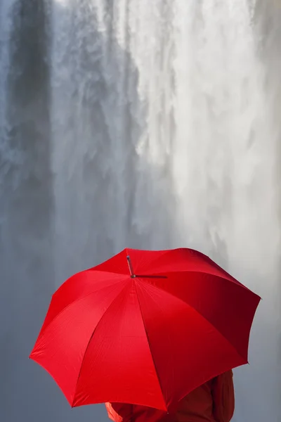 Kadın bir şelale önünde kırmızı bir şemsiye ile — Stok fotoğraf