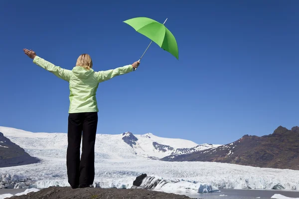 Frau mit grünem Regenschirm vor schmelzendem Gletscher — Stockfoto