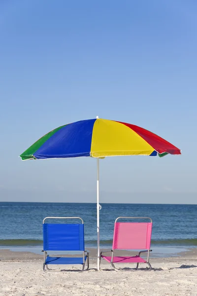 Цветной пляжный зонтик с розовыми и голубыми шезлонгами — стоковое фото