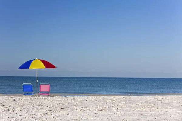 Цветной пляжный зонтик с розовыми и голубыми шезлонгами — стоковое фото