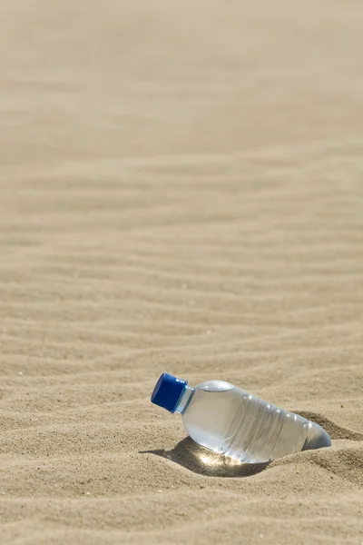 Botella de agua en un desierto de arena —  Fotos de Stock