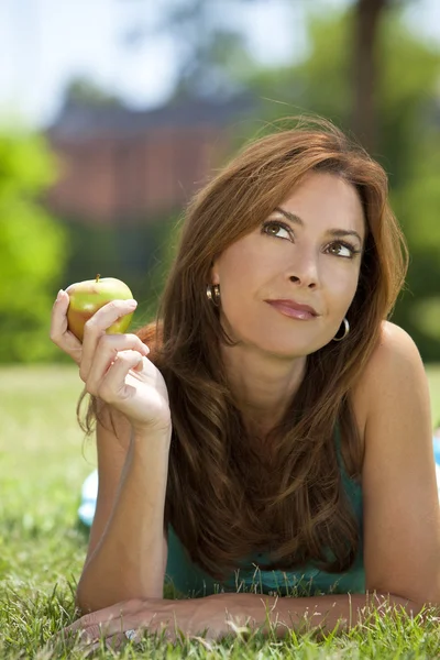 Όμορφη γυναίκα έξω από τρώει ένα μήλο και σκέψης — Φωτογραφία Αρχείου