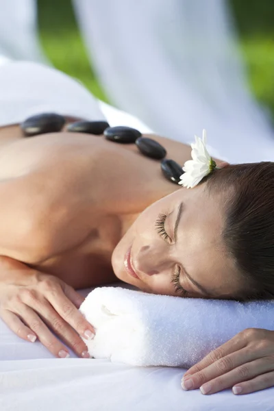 Mujer relajante en el spa de salud teniendo masaje de tratamiento de piedra caliente —  Fotos de Stock