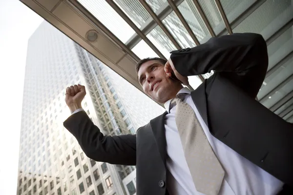 Gelukkig zakenman vieren op mobiele telefoon in de stad — Stockfoto