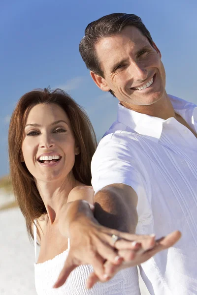 Привабливі пара, сміючись, тримаючись за руки на пляжі — стокове фото