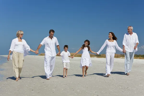Drie generaties van familie wandelen bedrijf handen op strand — Stockfoto