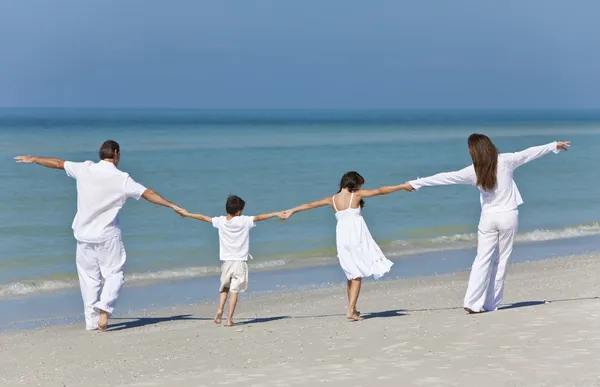 Matka, otec i děti rodina drží za ruce na pláži — Stock fotografie