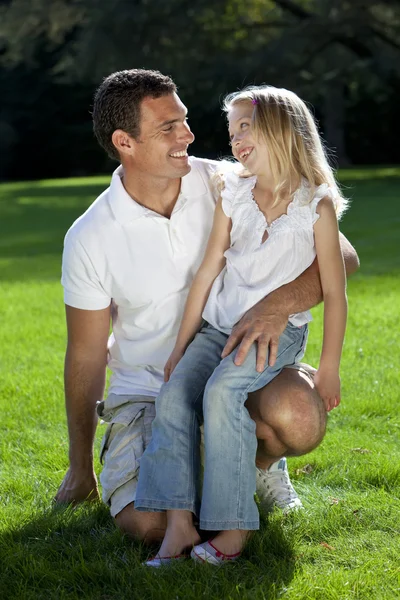 Vader en dochter op knie glimlachend in een park — Stockfoto