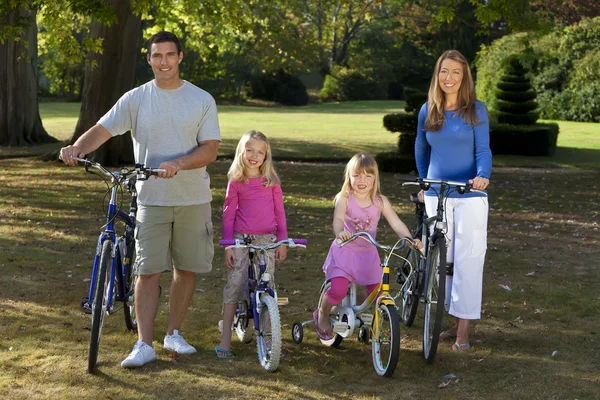 Lycklig familj ridning cyklar i en park — Stockfoto
