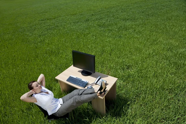 Femme se relaxant à un bureau dans un champ vert — Photo