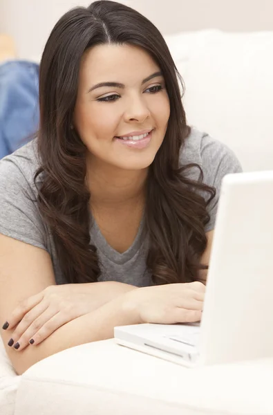 Vacker spansktalande kvinna på soffa använder bärbar dator Stockfoto