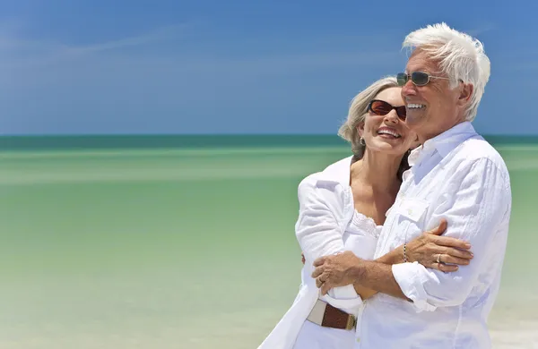 Lyckliga äldre paret ser till havet på en tropisk strand Stockbild
