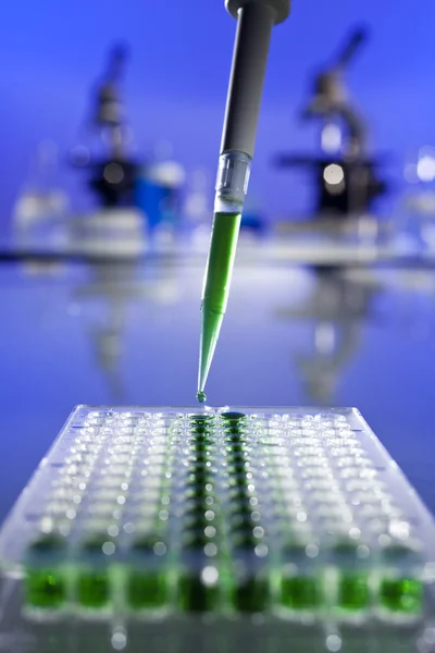 Investigación científica de solución verde con una pipeta y una placa celular — Foto de Stock