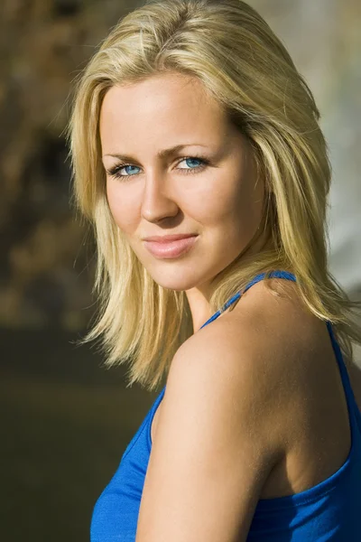 Mooie blonde vrouw in blauwe jurk badend in gouden zon — Stockfoto