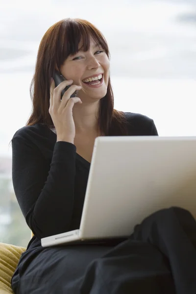Hermosa mujer feliz usando ordenador portátil y teléfono en casa —  Fotos de Stock