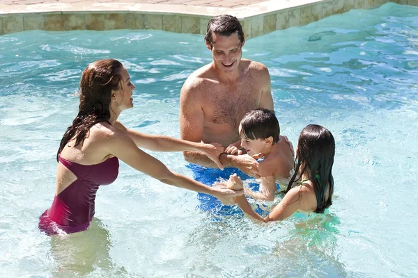Ευτυχισμένη οικογένεια με δύο παιδιά που παίζουν στην πισίνα — Φωτογραφία Αρχείου