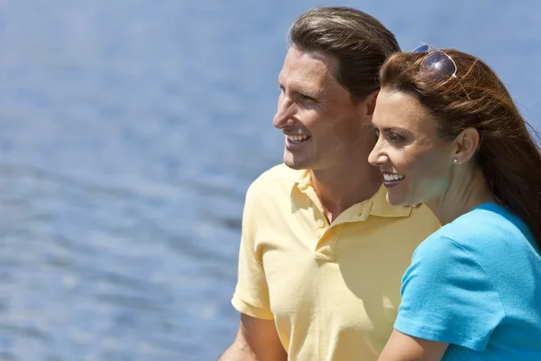 Gelukkige man en vrouw paar zitten buiten door water — Stockfoto