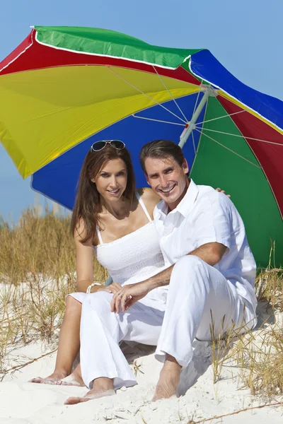 Homem & mulher casal sob multi colorido guarda-chuva na praia — Fotografia de Stock