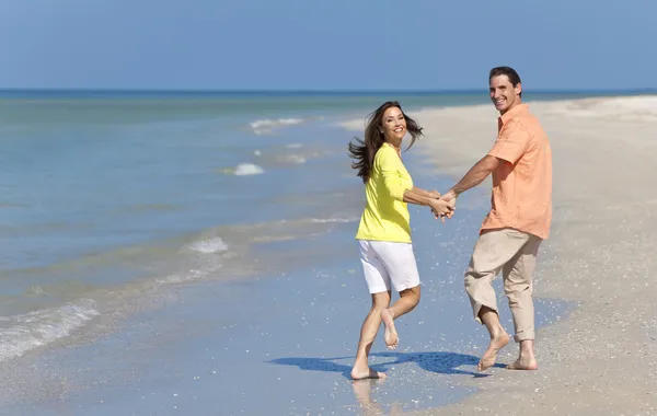 Щаслива пара працює, тримаючись за руки на пляжі — стокове фото
