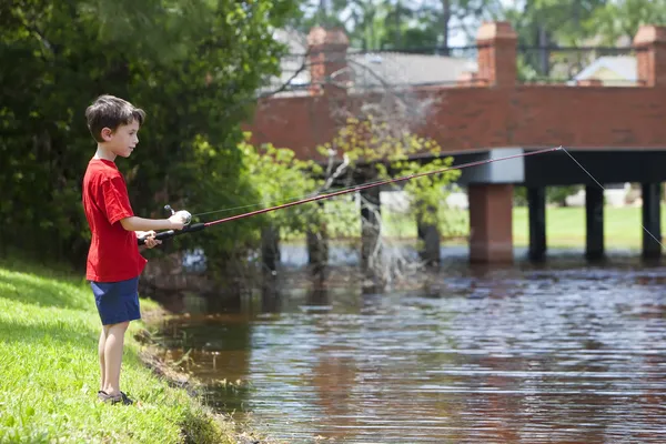 Giovane ragazzo pesca su un fiume — Foto Stock