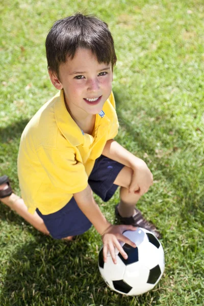 Мальчик на улице играет в футбол или футбольный мяч — стоковое фото