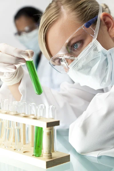 Vrouwelijke wetenschapper met reageerbuis van groene oplossing in laboratorium — Stockfoto