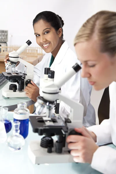 Kadın bilimsel araştırma ekibi bir laborator mikroskoplar kullanılarak — Stok fotoğraf