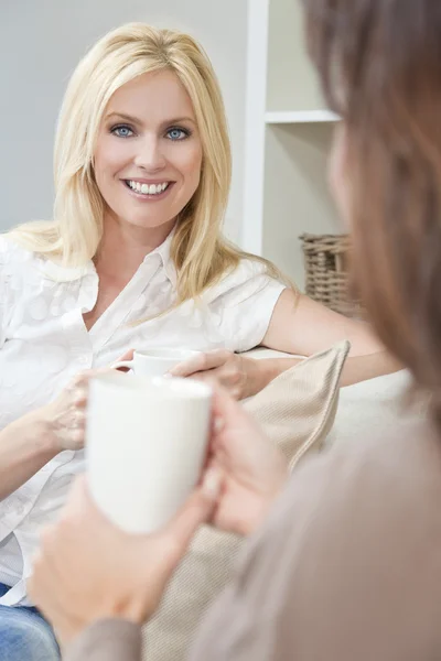 Twee mooie vrouwen vrienden drinken thee of koffie thuis — Stockfoto