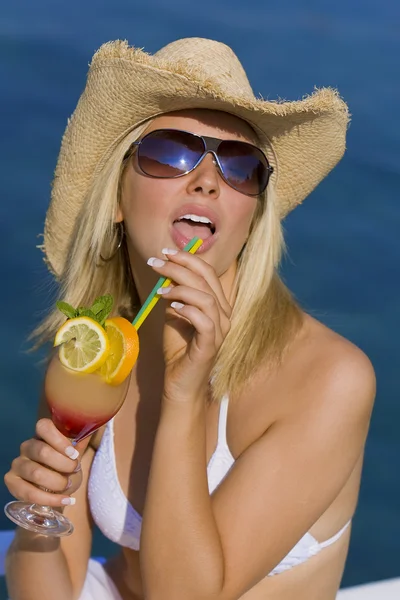 Prachtige blond meisje in bikini drinken cocktail door de zee — Stockfoto