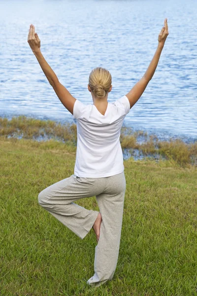 Piękna młoda kobieta praktykujących jogę przez spokojne jezioro niebieski — Zdjęcie stockowe