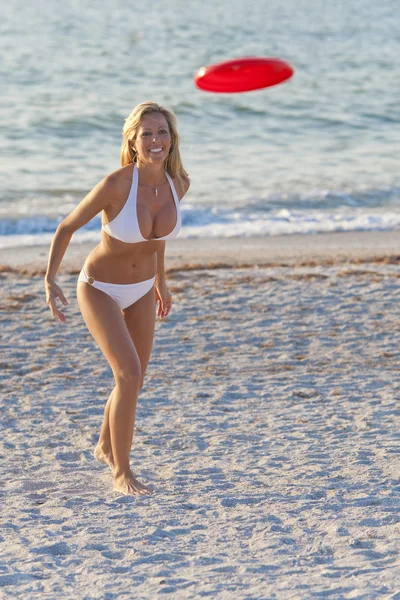 Vacker blond kvinna i bikini spela frisbee på stranden — Stockfoto
