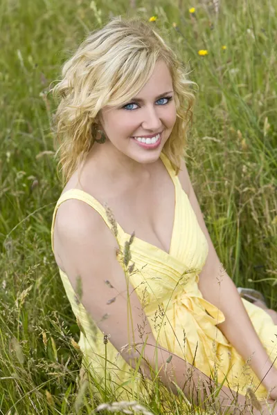Красива блондинка сидить у високій траві — стокове фото