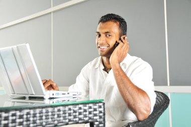 Indian Man with laptop talking on phone clipart