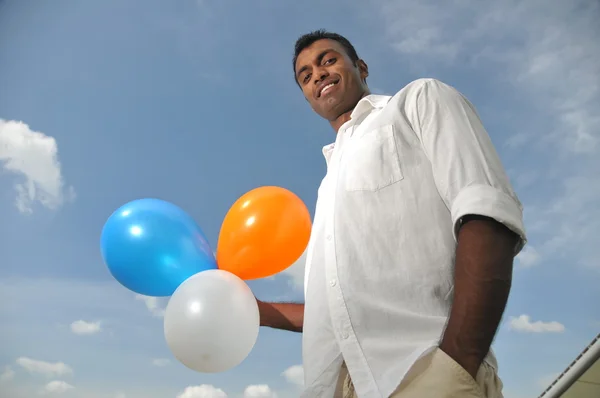 Indický muž držící barevné bubliny směřující na dálku — Stock fotografie