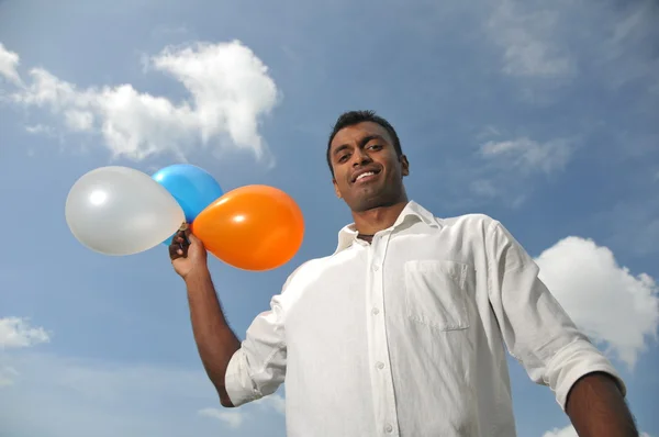 Індійський чоловік тримає різнокольорових кульок, вказуючи на відстані — стокове фото