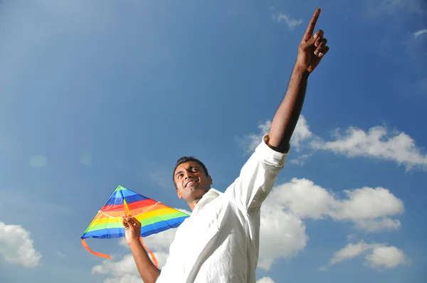 Homem indiano segurando uma pipa arco-íris apontando a uma distância — Fotografia de Stock