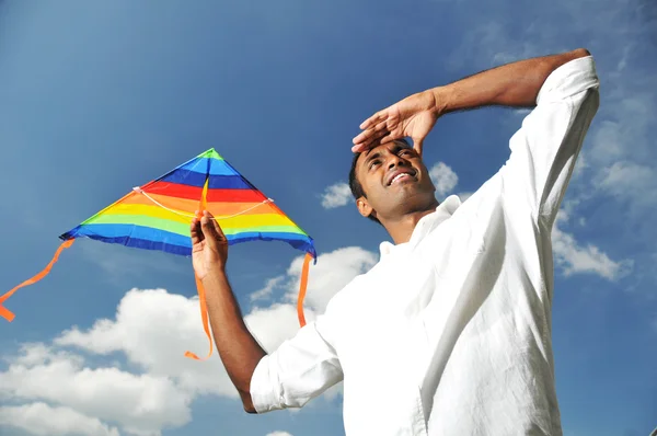 Uomo indiano in possesso di un aquilone arcobaleno guardando una distanza — Foto Stock