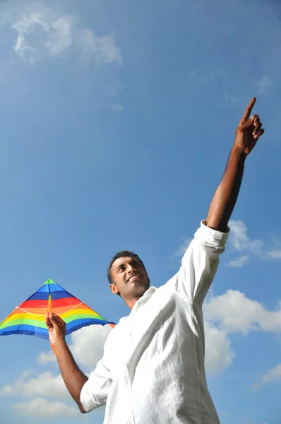 Indiano homem segurando um pipa arco-íris apontando — Fotografia de Stock
